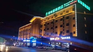 Een hotel met meerdere verdiepingen, een opvallende ingang en verlichte signage.