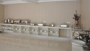 Een moderne hotelkamer met een lange buffetbar, witte planken en een schoon, minimalistisch design.
