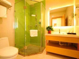 Un baño con ducha acristalada, inodoro blanco y tocador con espejo y lavabo.