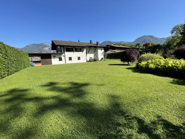 A house with a well-maintained lawn, a mountain in the background, and a clear sky.