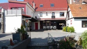 A two-story building with a red-tiled roof, a front entrance, and a small garden area with rocks and plants. - Haus Anna An Der Stadtmauer (Hanau)