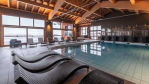 An indoor swimming pool with lounge chairs, large windows, and a wooden ceiling. - La Rosiere (Montvalezan)