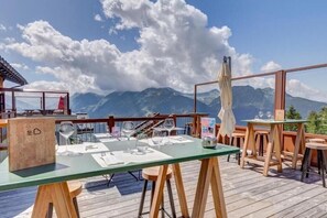 Een restaurant met terras, een houten dek en uitzicht op de bergen.
