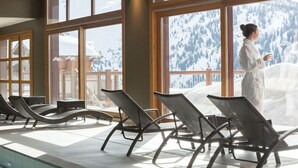 A spa area with large windows, lounge chairs, and a view of snow-covered mountains. - La Rosiere (Montvalezan)