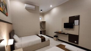 A hotel room with two beds, a TV mounted on the wall, and a small shelf with toiletries. - Hotel Orizatha (Mataram)