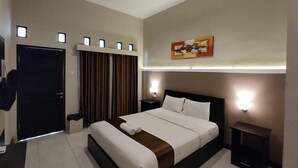 A modern hotel room with a large bed, a desk, a chair, a wardrobe, and a painting on the wall. - Hotel Orizatha (Mataram)