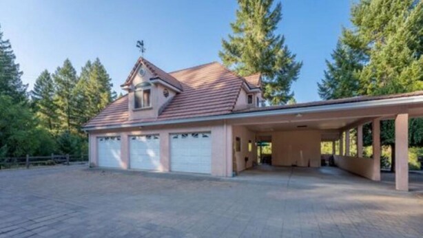 Una casa de dos pisos con garaje cubierto y entrada pavimentada.
