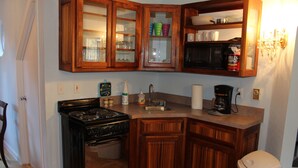 Una cocina con armarios de madera, estufa, microondas y cafetera.