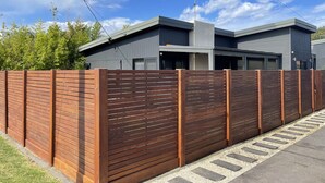 Una casa moderna de dos pisos con un cerco de madera, una antena parabólica y un garaje.