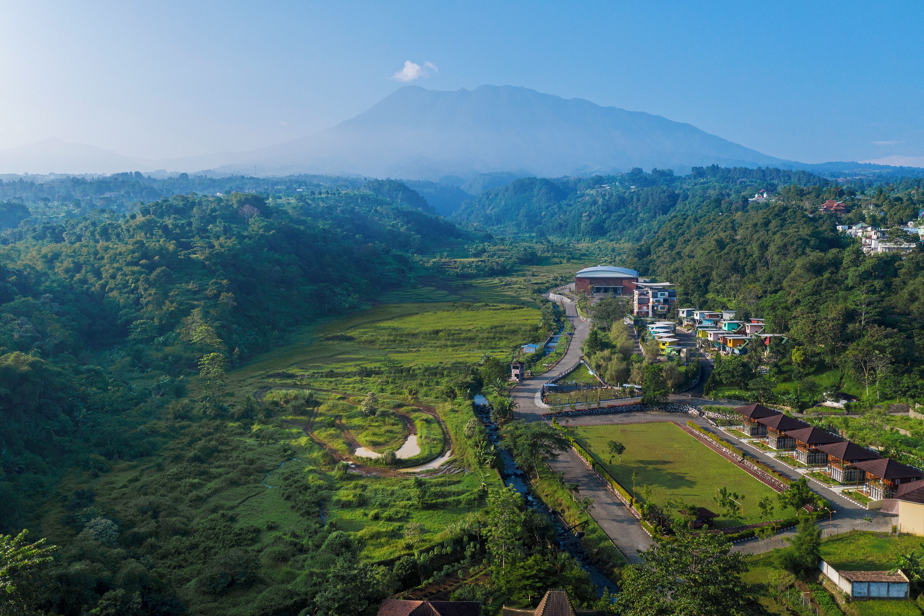 A hotel with a central courtyard, surrounded by lush greenery and a river.