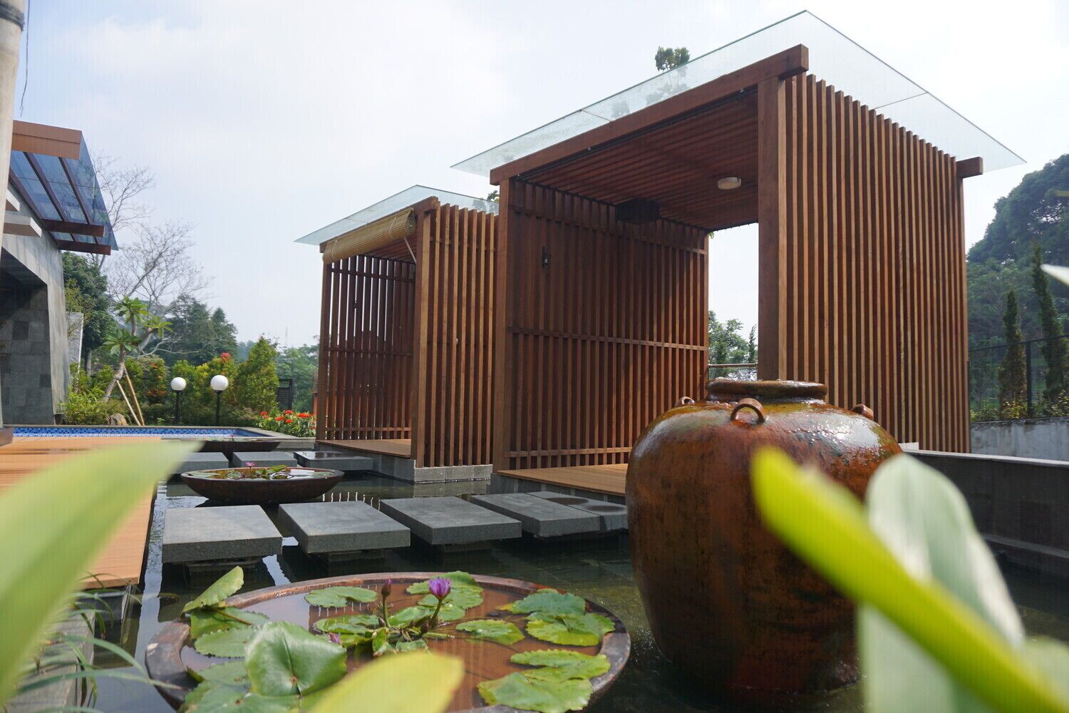 A traditional Japanese-style building with a wooden exterior and a glass roof, surrounded by a water feature with lotus plants.