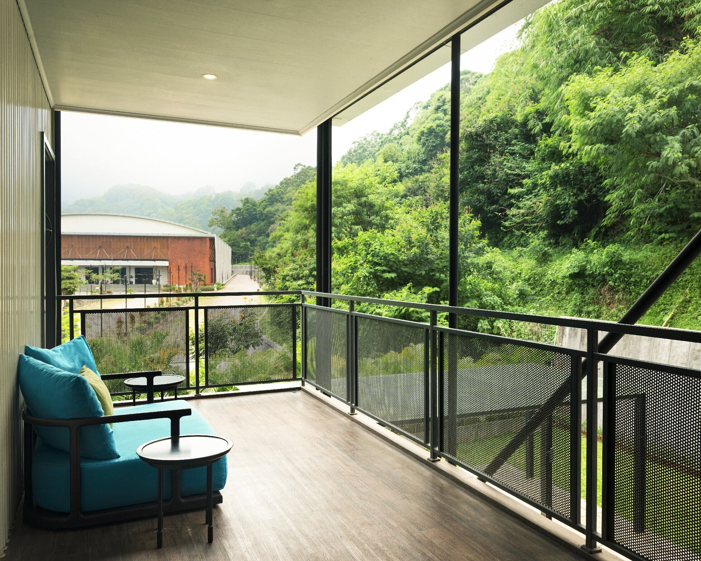 A balcony with a view of a forested area and a building in the background.
