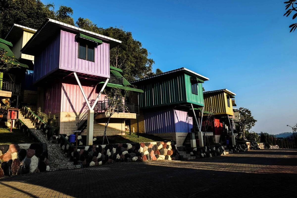 A row of colorful, elevated houses with a stone wall in front.