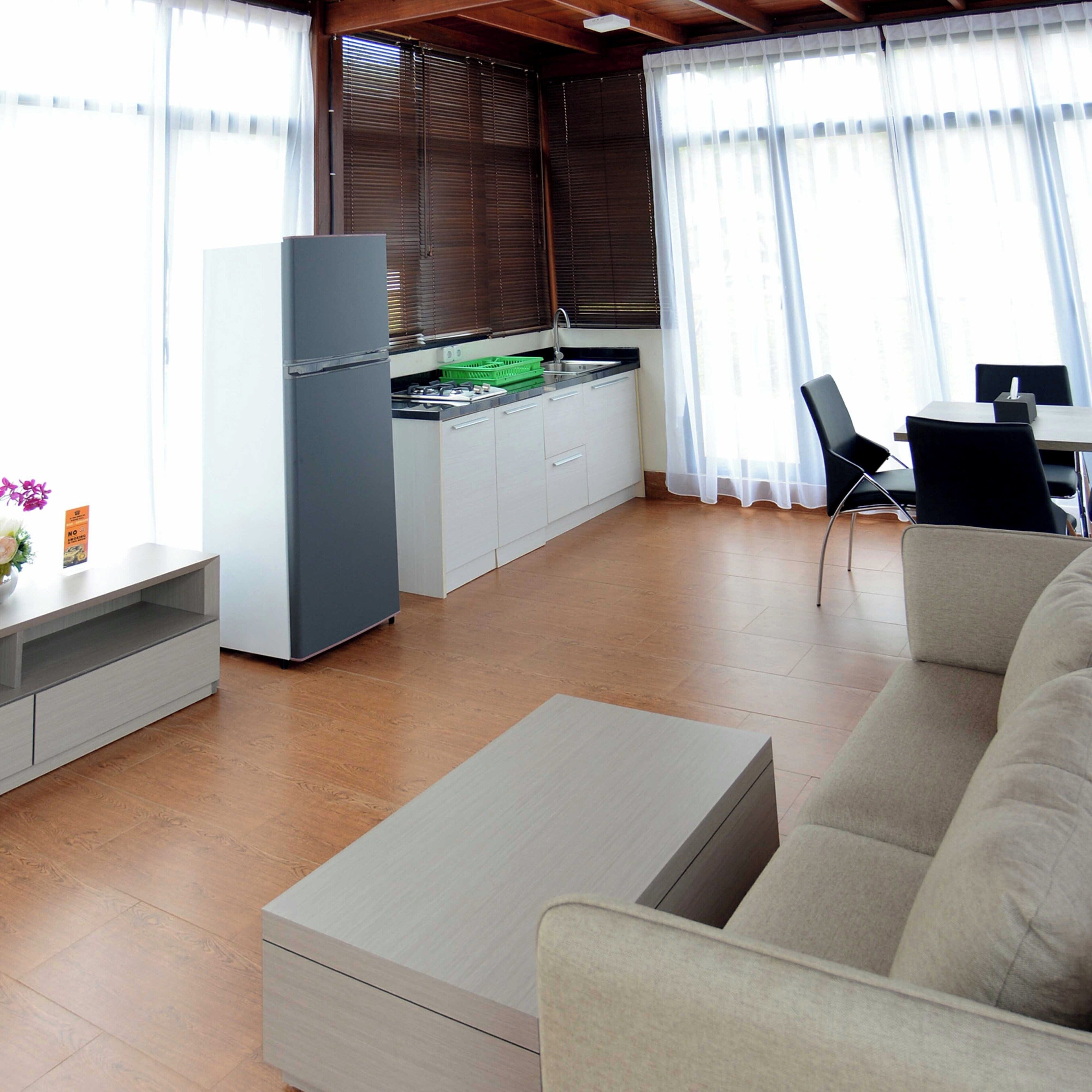 A modern kitchen with a refrigerator, sink, and cabinets. There is a dining area with a table and chairs.