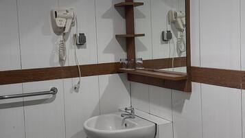 Un baño con lavamanos, espejo, toallero y cubo de basura.