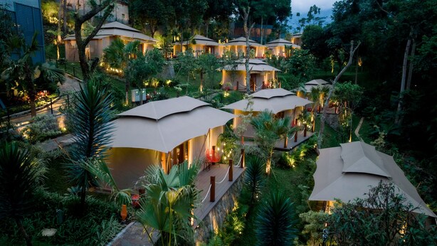 A resort with multiple overwater bungalows surrounded by lush greenery and palm trees. - JSI Resort (Megamendung)