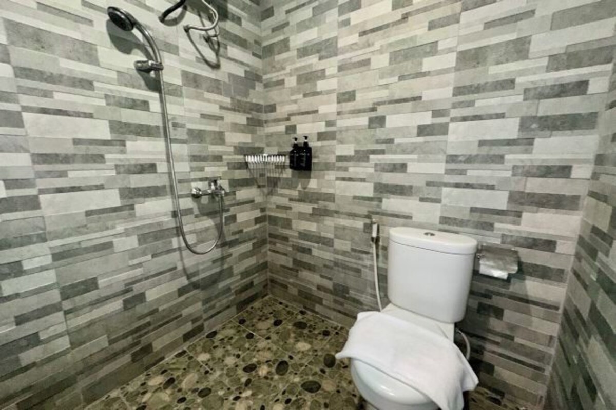 A bathroom with a shower, toilet, and tiled walls.
