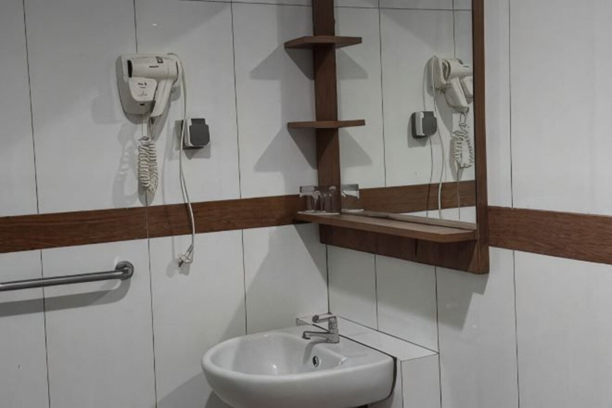 A bathroom with a sink, a mirror, and two hair dryers mounted on the wall.