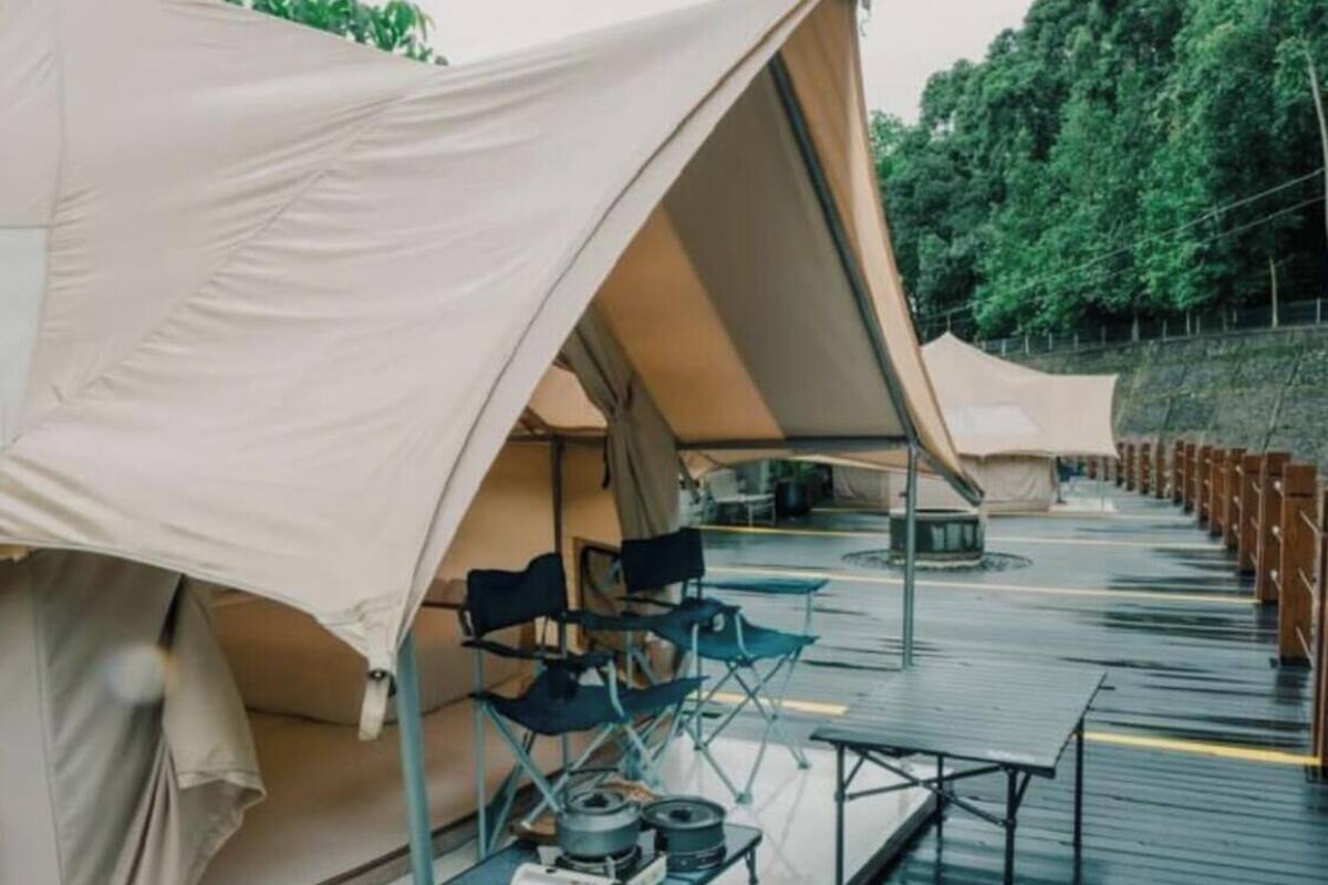 A row of tents with camping gear and tables on a wooden deck.