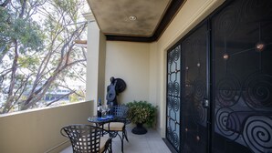 Un balcon avec une table, des chaises, une guitare et une plante en pot.