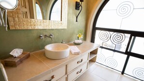 Une salle de bain avec un grand lavabo, un miroir, un porte-serviettes et une fenêtre donnant sur un paysage agréable.