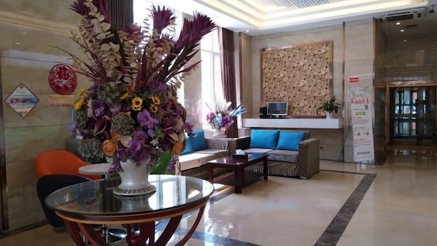 A modern lobby with a round glass table, a sofa with blue cushions, and a decorative floral arrangement.