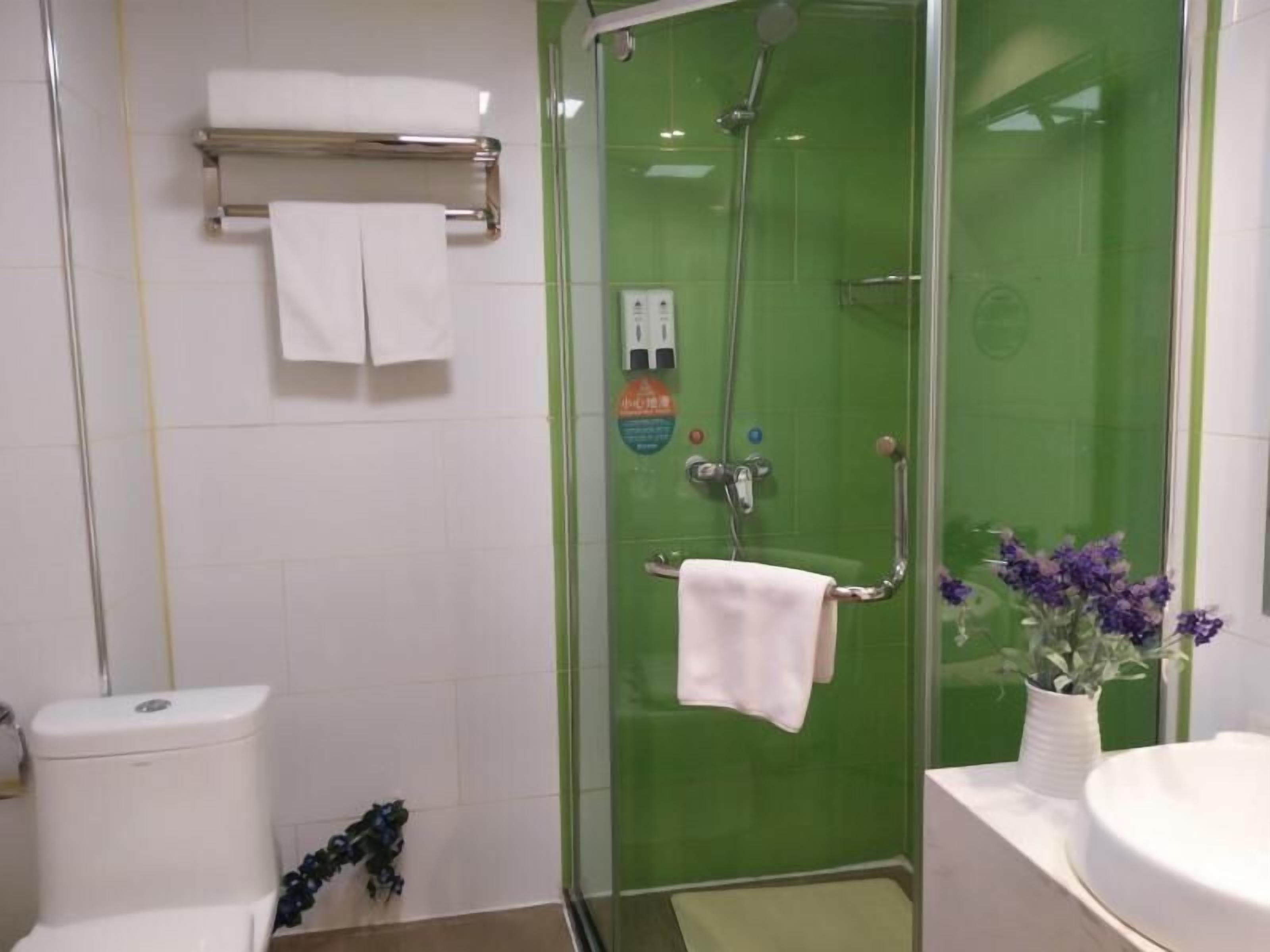 Un baño con ducha de vidrio, inodoro, lavamanos y toallero.