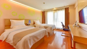 A hotel room with two beds, a desk, and a chair.