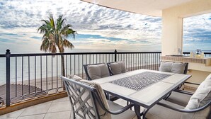A balcony with a table and chairs, a palm tree, and a view of the sea. - Sonoran Sky Resort 310 Vacationer's Dream Getaway Ocean Front Condo (Puerto Peñasco)