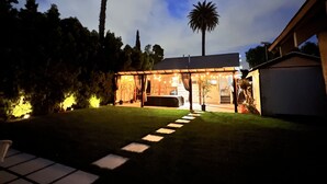 Una casa moderna con un patio bien iluminado, cielo despejado y una palmera.