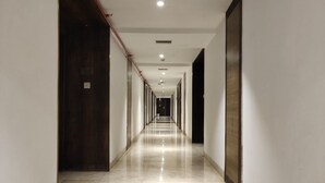 Un pasillo largo y estrecho con piso de mármol brillante, paredes blancas y puertas a ambos lados.