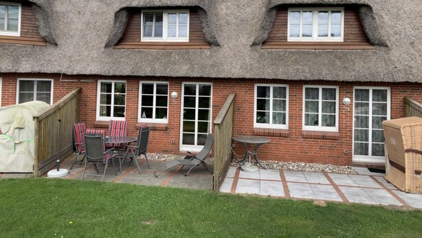A thatched-roof cottage with a brick exterior, multiple windows, and outdoor seating. - Daggys Huus - Holiday home Daggy (Nordstrand)