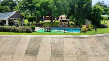 A swimming pool with a surrounding deck, a small gazebo, and lush greenery.