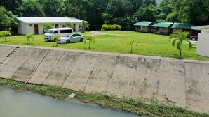 A hotel with a grassy lawn, a swimming pool, and a few parked cars. - Monty's Riverside View Resort by Cocotel (San Antonio)