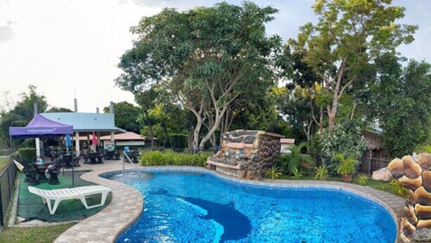 A swimming pool with a stone edge, surrounded by greenery and a gazebo. - Monty's Riverside View Resort by Cocotel (San Antonio)