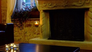 A room with a stone fireplace, a table with candles, and a window with curtains. - Picos de Europa (Cabrales)