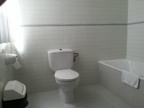 A small, clean bathroom with a toilet, a bathtub, and a towel hanging on the wall. - Picos de Europa (Cabrales)