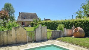 A swimming pool with a tiled deck, a concrete wall, and a large ceramic pot. - Cultural Treasure in Dordogne with furries (St. Medard D'excideuil)