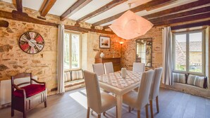 A rustic dining room with a stone wall, wooden beams, a round clock, and a table with chairs. - Cultural Treasure in Dordogne with furries (St. Medard D'excideuil)