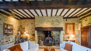 A rustic room with stone walls, a fireplace, two white sofas with brown cushions, and a wooden coffee table. - Cultural Treasure in Dordogne with furries (St. Medard D'excideuil)