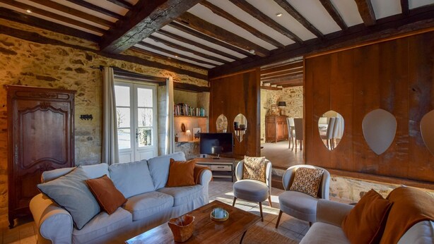 A cozy living room with a stone wall, wooden beams, a sofa set, a coffee table, and a television. - Cultural Treasure in Dordogne with furries (St. Medard D'excideuil)