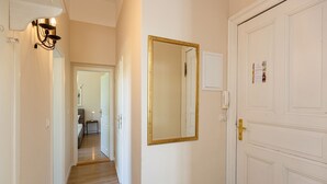 Un couloir doté d’un plancher en bois, d’une porte blanche avec un cadre doré et d’un miroir fixé au mur.