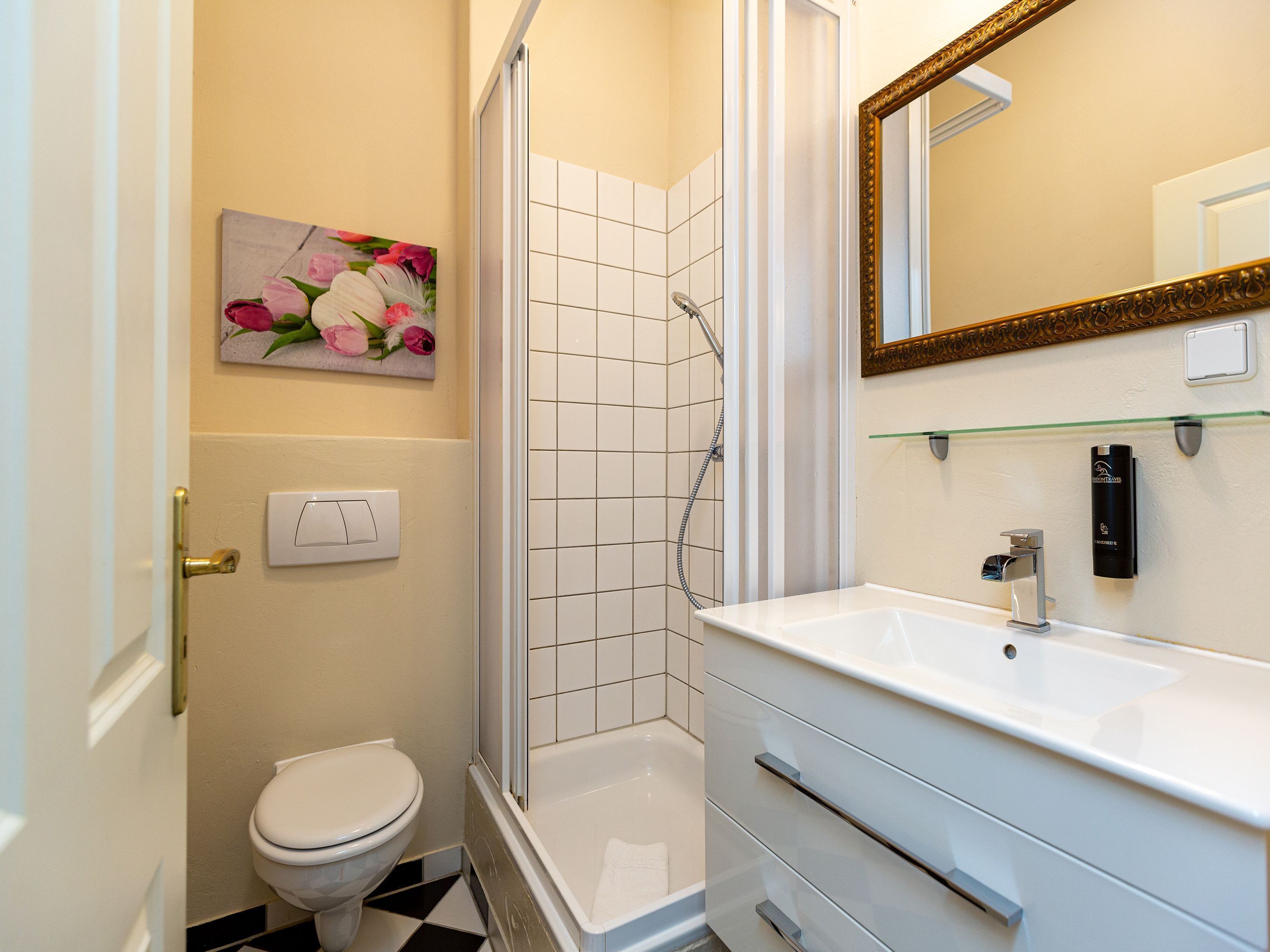 Et badeværelse med toilet, brusebad, vask og spejl.