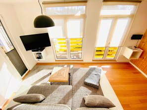 Uma sala de estar moderna com sofá, mesa de centro e TV fixada na parede.