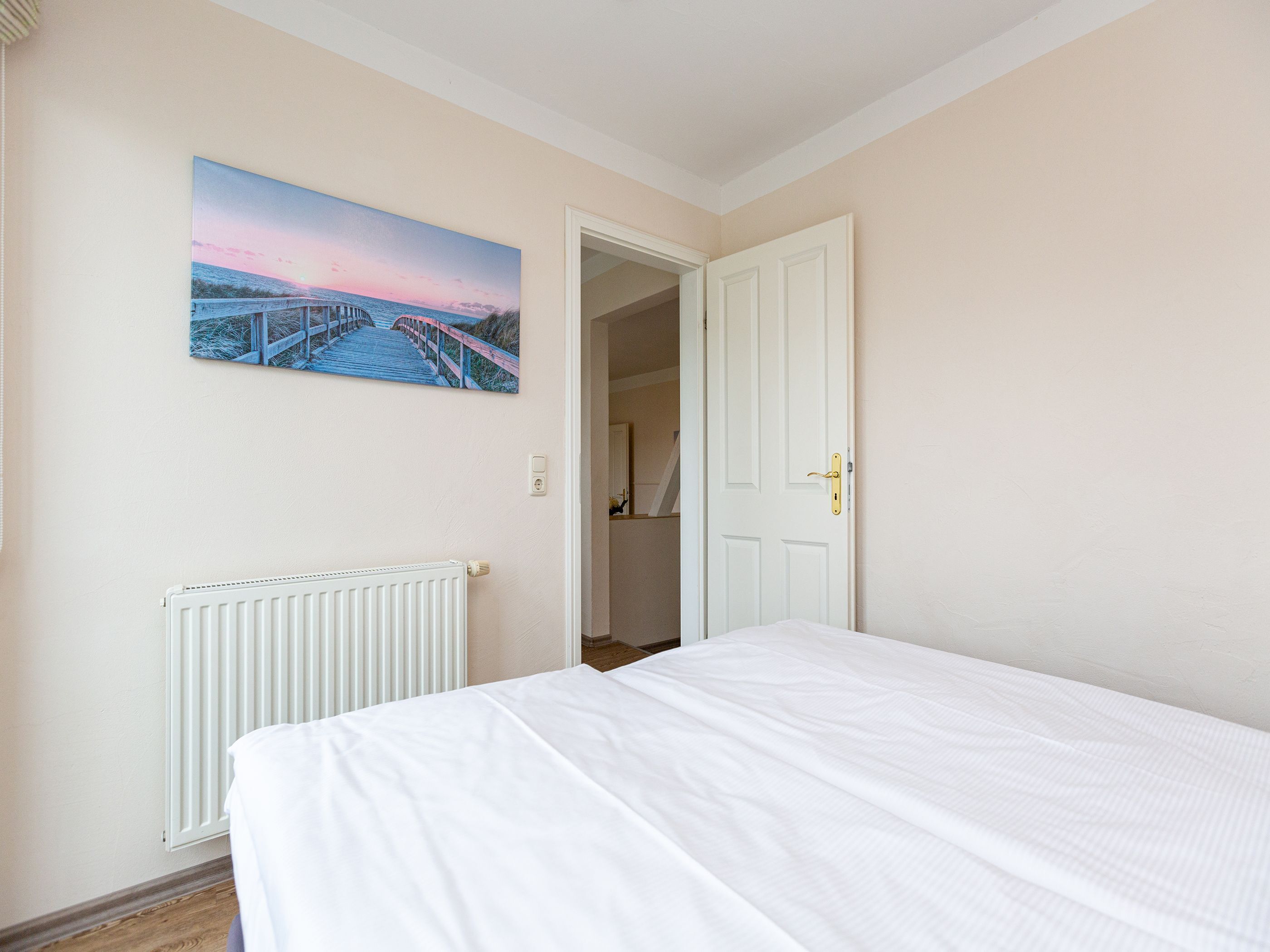 Ein Schlafzimmer mit Bett, Heizkörper, Tür und einem Gemälde an der Wand.
