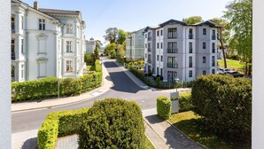 Une rue résidentielle bordée d’immeubles à plusieurs étages, avec un ciel dégagé et une route bien visible qui s’étend au loin.