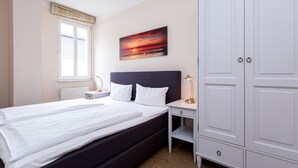A bedroom with a bed, a nightstand, a desk, and a wardrobe. - Villa Amelia, apt. 09 (Heringsdorf)