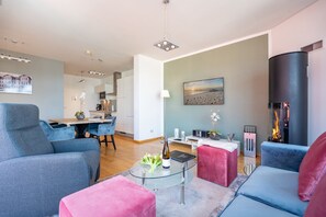 Uma sala de estar moderna com uma mesa de centro de vidro, uma lareira e um espaço de refeições com cadeiras azuis.