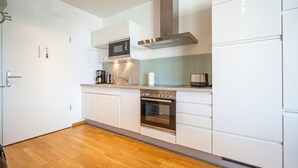 Une cuisine moderne avec des meubles blancs, des appareils en acier inoxydable et un plancher en bois.