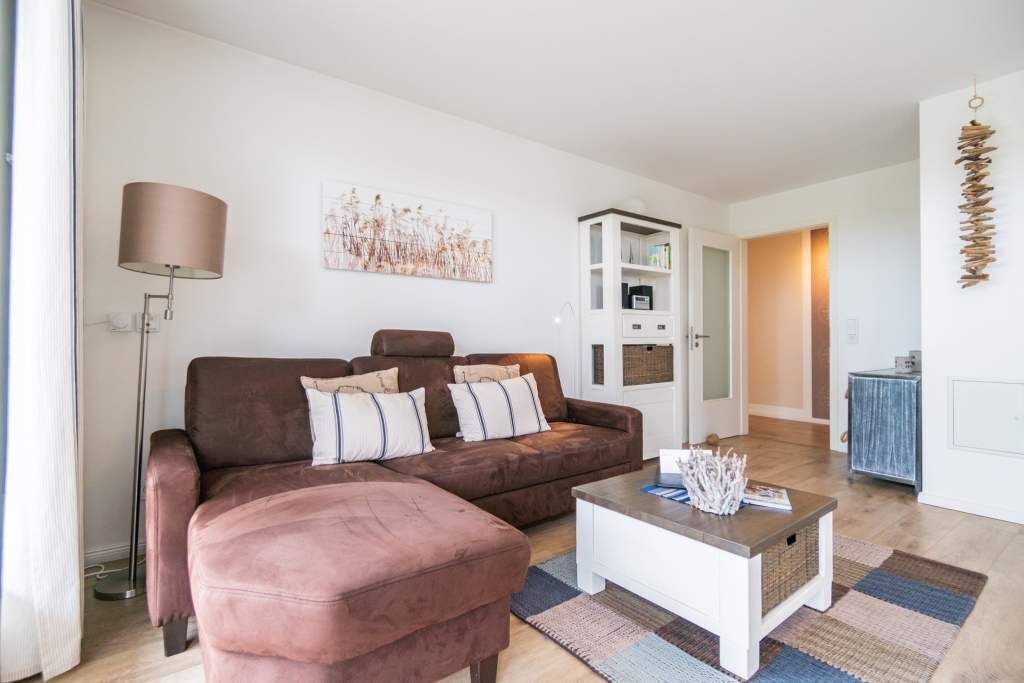 A living room with a brown sofa, a white coffee table, and a floor lamp.